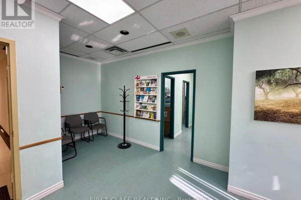 Small waiting area with light blue walls, grey chairs, and a coat rack. - 412 - 4002 Sheppard Avenue E, Toronto