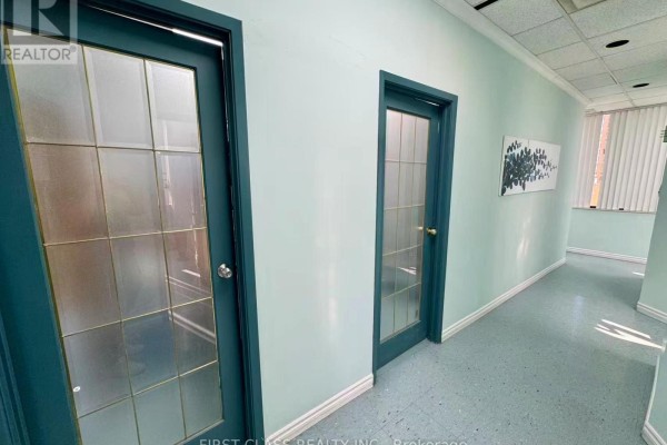 Commercial building hallway with cream walls, two pink elevators, and tiled floor. - 412 - 4002 Sheppard Avenue E, Toronto