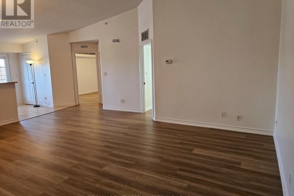 Living room with wood-look laminate flooring, white walls, and doorways to other rooms. - 412 - 4025 Kilmer Drive, Burlington