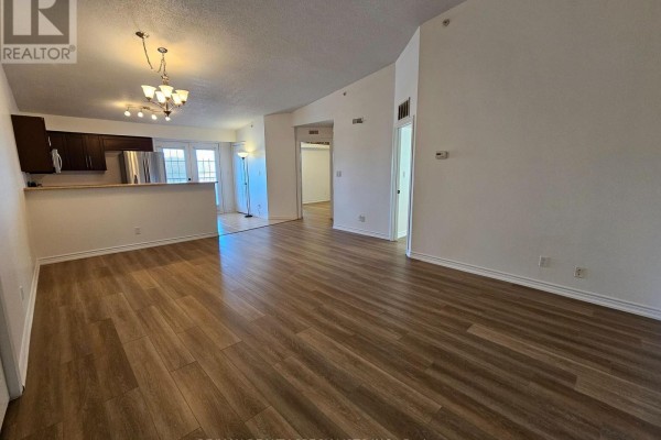 Living room with wood-look laminate flooring, showing a partial view of the kitchen area. - 412 - 4025 Kilmer Drive, Burlington