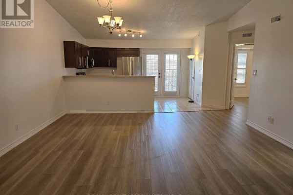 Living room and open-concept kitchen with dark wood cabinets and stainless steel appliances. - 412 - 4025 Kilmer Drive, Burlington