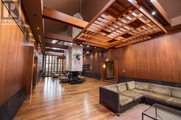Lobby with wood paneling, a large stone fireplace with mounted moose head, and seating areas. - 412 - 4080 Living Arts Drive, Mississauga