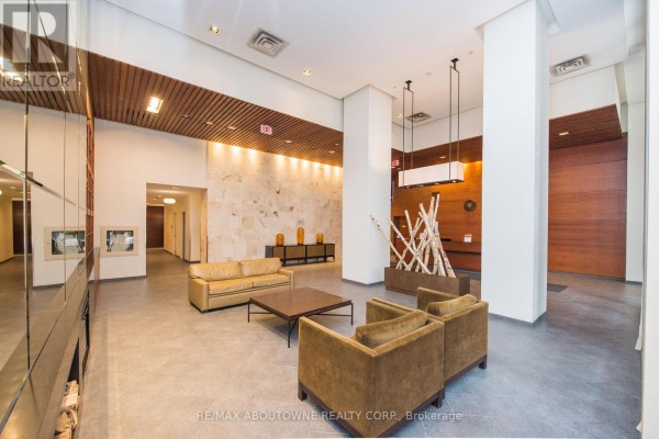 Lobby with light stone accent wall, tan sofas, and modern light fixtures. - 412 - 4080 Living Arts Drive, Mississauga