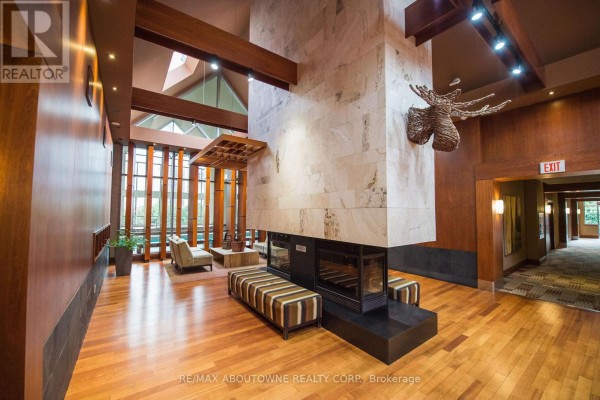 Interior view of a spacious lobby with a large stone fireplace, wood accents, and seating. - 412 - 4080 Living Arts Drive, Mississauga