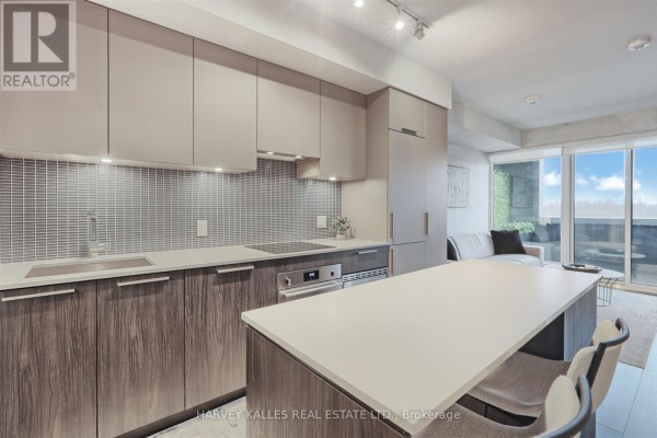 Living room with light grey sectional, television on shelf, and sliding glass doors to balcony. - 412 - 4208 Dundas Street W, Toronto