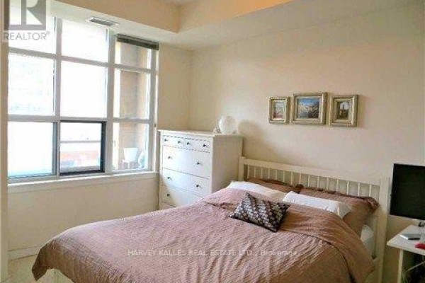 Bedroom with a queen bed, white dresser, and large window. - 412 - 438 Richmond Street W, Toronto