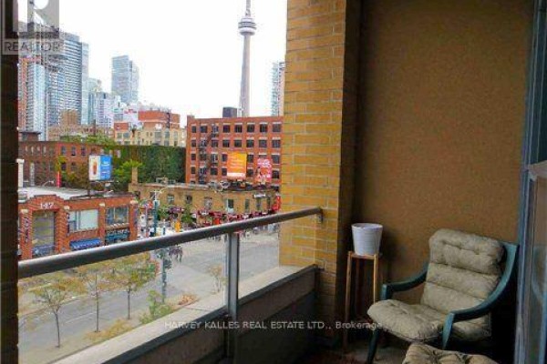 Balcony overlooking a city street with a chair and view of the CN Tower. - 412 - 438 Richmond Street W, Toronto
