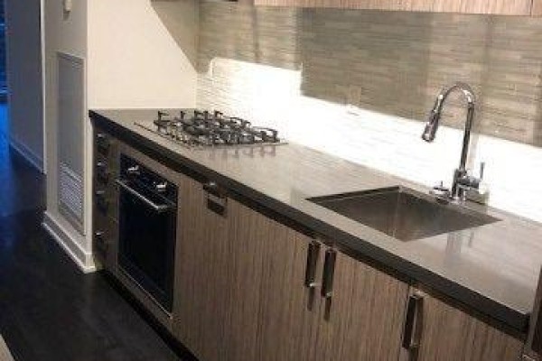 Kitchen counter with gas stovetop, oven, sink, and grey tiled backsplash. - 412 - 501 St Clair Avenue W, Toronto