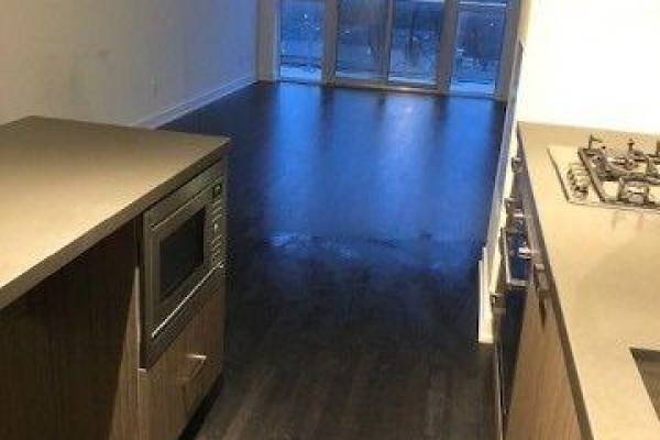 Kitchen island with built-in microwave and view of living room and balcony doors. - 412 - 501 St Clair Avenue W, Toronto