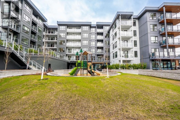 Apartment building complex with a grassy common area and a children's playground. - 412 3596 Malsum Drive, North Vancouver