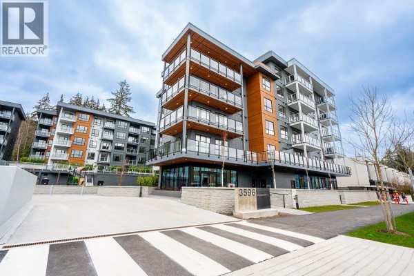 Exterior view of a modern apartment building with balconies and wood accents. - 412 3596 Malsum Drive, North Vancouver