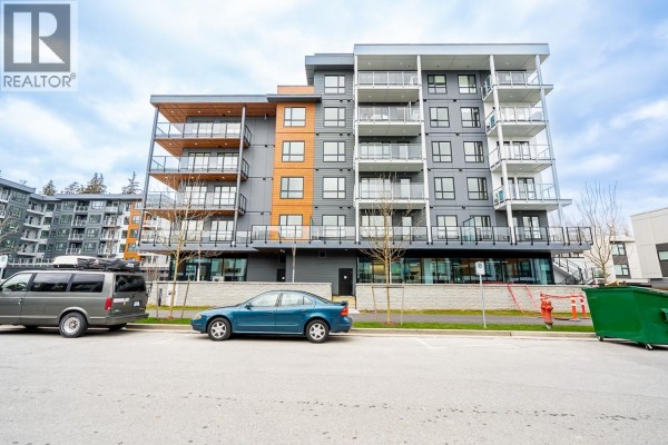 Street view of the apartment building with parked cars and landscaping. - 412 3596 Malsum Drive, North Vancouver