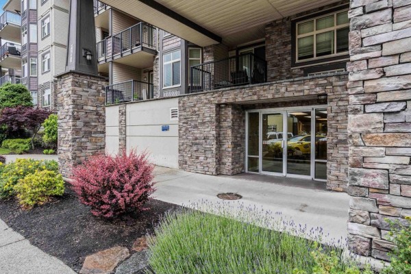 Close-up of the apartment building entrance with stone facade and glass doors. - 412 45893 Chesterfield Avenue, Chilliwack Downtown, Chilliwack