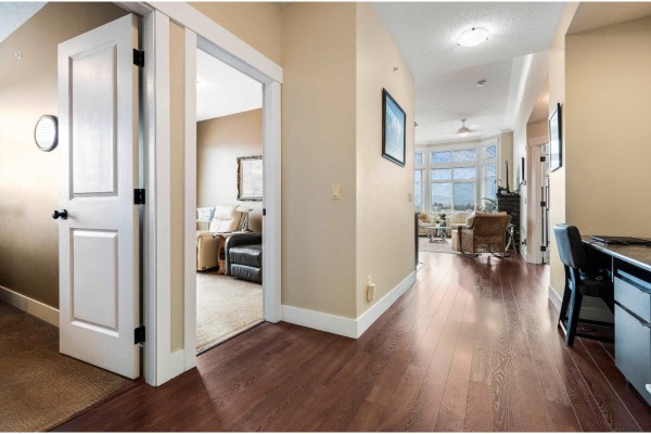 Interior hallway with dark wood floors, doors, and a desk, opening to a living area. - 412 45893 Chesterfield Avenue, Chilliwack Downtown, Chilliwack