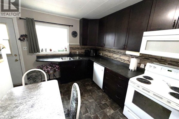 Small bedroom with a single bed, wooden dresser, and two windows with blinds. - 412 Main Street, Hudson Bay