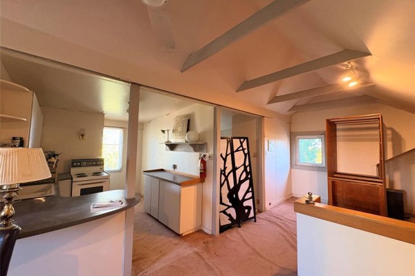 Interior view of a room with a kitchenette, cabinets, and a decorative screen divider. - 412 Wardlaw Avenue, Winnipeg