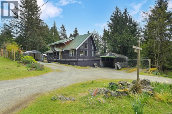 Driveway view of the house with a carport and greenhouse, a wooden fence, and a sign indicating the address 412. - 412 Wood Dale Dr, Mayne Island