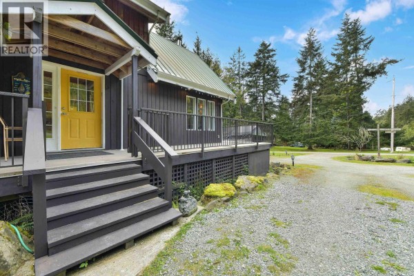 Close-up view of the front entrance stairs and yellow front door with windows. - 412 Wood Dale Drive, Mayne Island