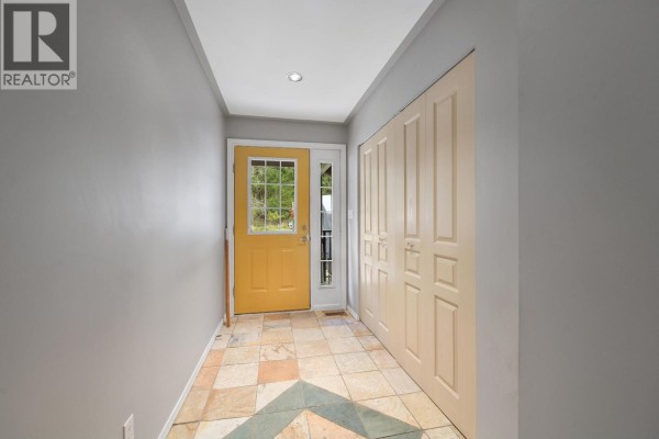 Interior view of an entryway with beige double doors on the right and a yellow front door. - 412 Wood Dale Drive, Mayne Island