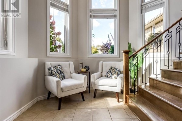 Cozy sitting area with two white armchairs, side table, and staircase. - 4120 Heritage Drive, Hanmer