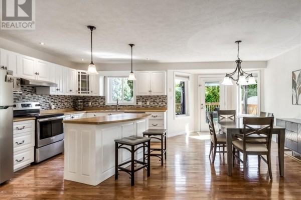 Open-concept kitchen and dining area with white cabinets, island, and hardwood floors. - 4120 Heritage Drive, Hanmer