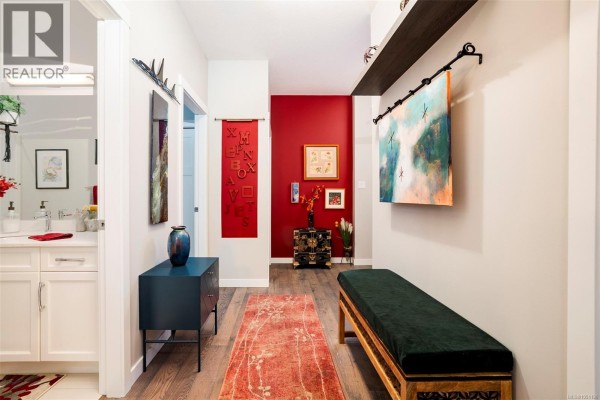 Interior hallway with a navy blue cabinet, red accent wall, and wooden floors. - 4128 Emerald Woods Pl, Nanaimo
