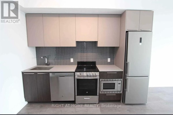 Kitchen with modern cabinetry, stainless steel appliances, and grey tiled backsplash. - 413 - 20 Brin Drive, Toronto