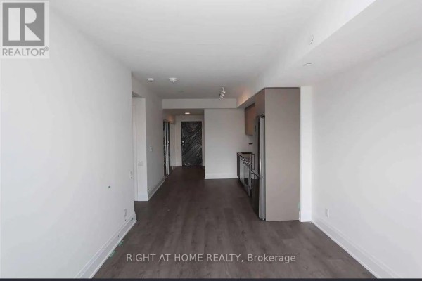 Hallway view of the open concept living space and kitchen with dark wood flooring. - 413 - 20 Brin Drive, Toronto