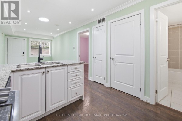 View of the kitchen island, white cabinets, and doorways leading to other rooms. - 413 - 8 Drummond Street, Toronto