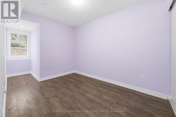 Bedroom with light purple walls, dark wood laminate flooring, and a window with blinds. - 413 - 8 Drummond Street, Toronto