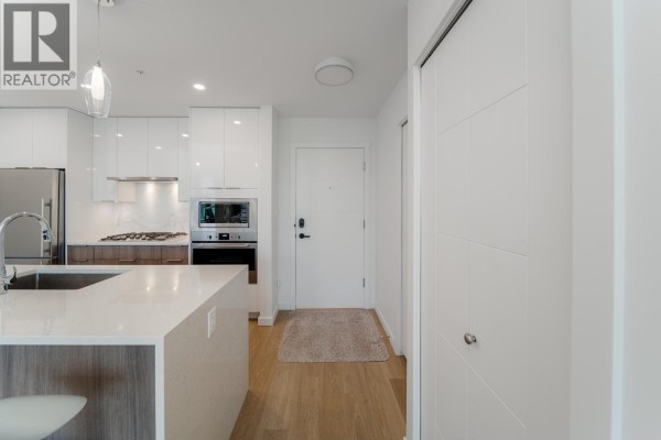 Open concept living room and kitchen with white cabinets and island. - 413 11641 227 Street, Maple Ridge