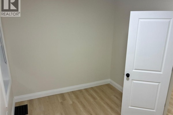 View from the hallway into the open-concept living area and kitchen with light wood floors. - 413 Concession Street Unit# Main, Hamilton