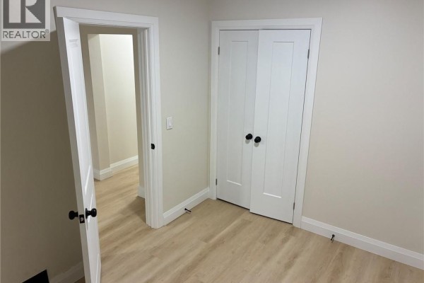 Interior view of a hallway with doors, beige walls, and light wood laminate flooring. - 413 Concession Street Unit# Main, Hamilton