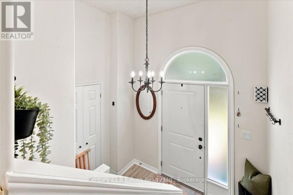 Interior entryway with white double doors, arched window, chandelier, and plant. - 413 Irwin Street, Midland