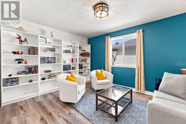 Living room with white bookshelves, two white chairs, coffee table, and teal accent wall. - 413 Irwin Street, Midland