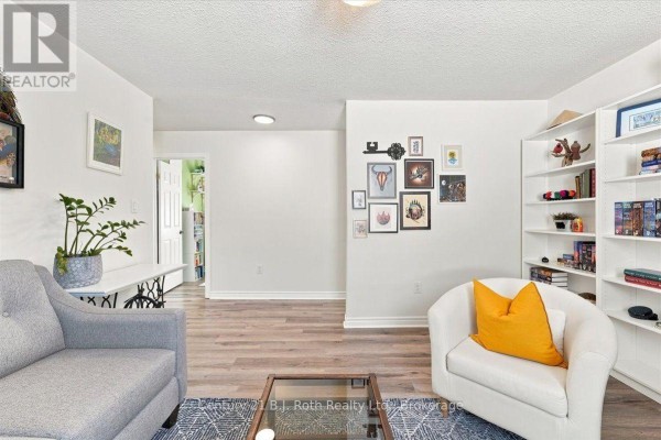 Living room with a grey sofa, white accent chair, coffee table, and bookshelves. - 413 Irwin Street, Midland