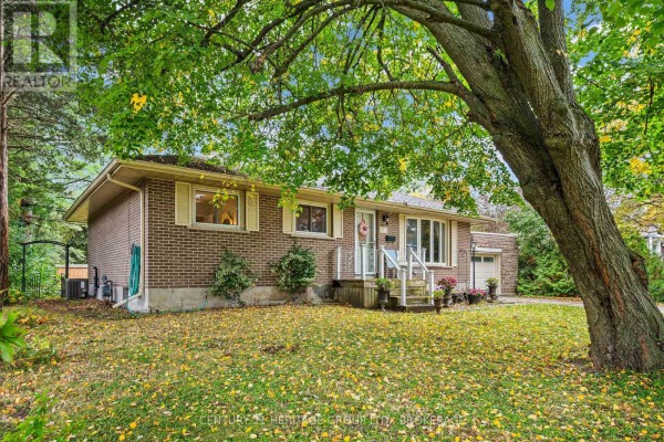 Side view of a brick bungalow showing the garage and front entrance. - 413 Maple Ridge Drive, Kingston