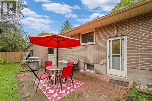 Rear of the brick bungalow with a patio, door, and basement windows. - 413 Maple Ridge Drive, Kingston