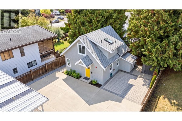 Aerial view of the house from the side, showing the roofline, driveway, and backyard. - 413 Seventh Avenue, New Westminster