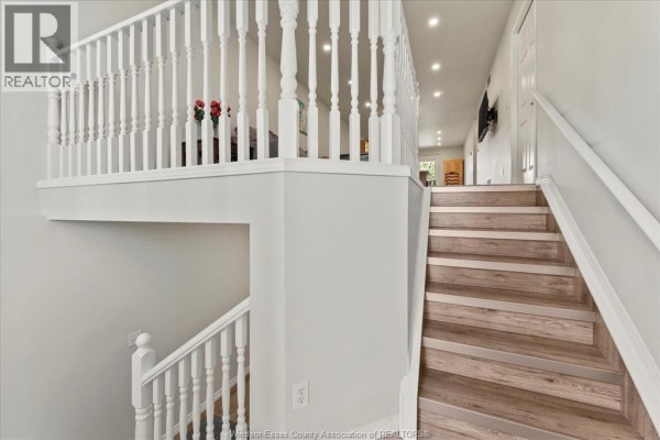 Staircase with white railings and wood-look laminate treads connecting two levels. - 4135 St. Clair, Lasalle