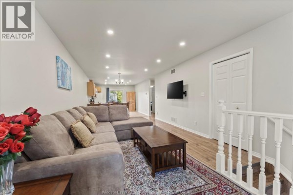 Living room with a sectional sofa, coffee table, and a television mounted on the wall. - 4135 St. Clair, Lasalle