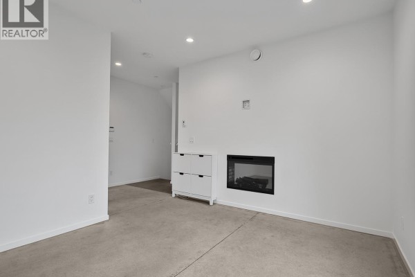 Room with white walls, concrete floor, and a modern gas fireplace. - 4136 Beatrice Street, Vancouver