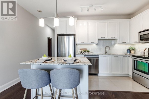 White kitchen with granite countertops, stainless steel appliances, and a breakfast island with two grey stools. - 414 - 2470 Prince Michael Drive, Oakville