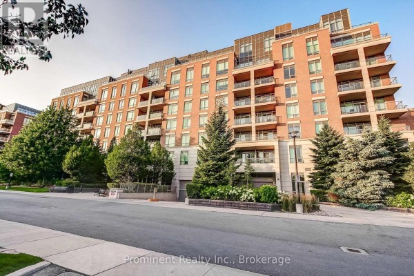 Exterior view of a multi-story brick apartment building surrounded by mature trees and landscaping. - 414 - 2470 Prince Michael Drive, Oakville