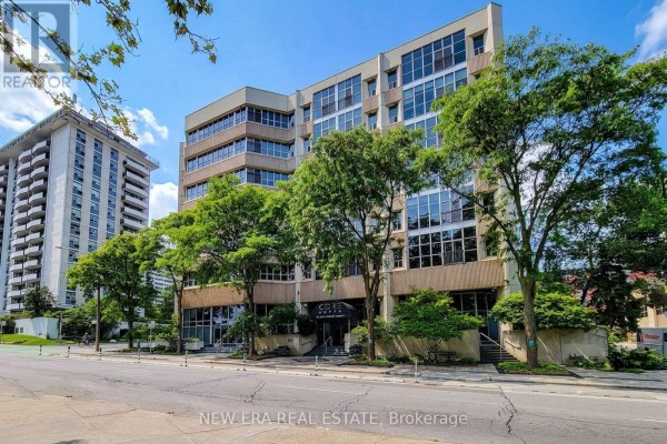 Wide exterior view of the Core Lofts apartment building with surrounding trees and street. - 414 - 66 Bay Street S, Hamilton