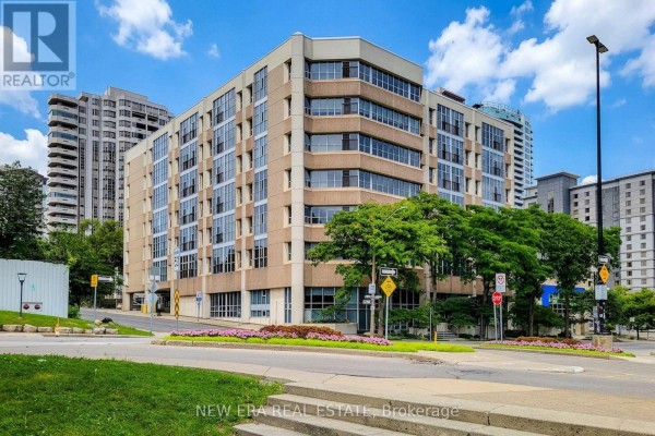Apartment building exterior with beige concrete facade, glass windows, and trees in foreground. - 414 - 66 Bay Street S, Hamilton