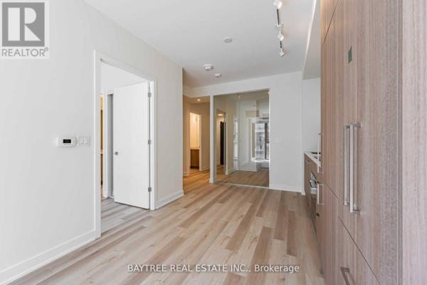 Interior view of apartment hallway with doorways, leading to a glass-partitioned room. - 414 - 840 St Clair Avenue W, Toronto