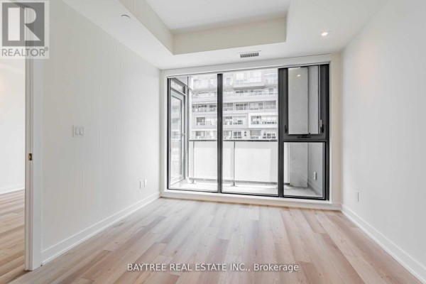 Bright living room with light wood floors and a large window overlooking an urban cityscape. - 414 - 840 St Clair Avenue W, Toronto