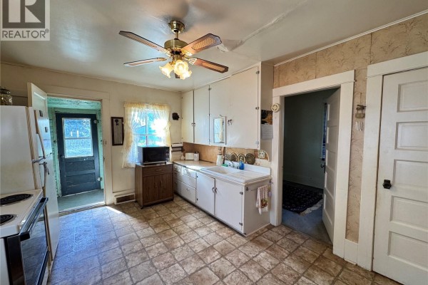 View of white doors, green wooden walls, a chest freezer, and a pineapple door knocker. - 414 4th Avenue E, Biggar