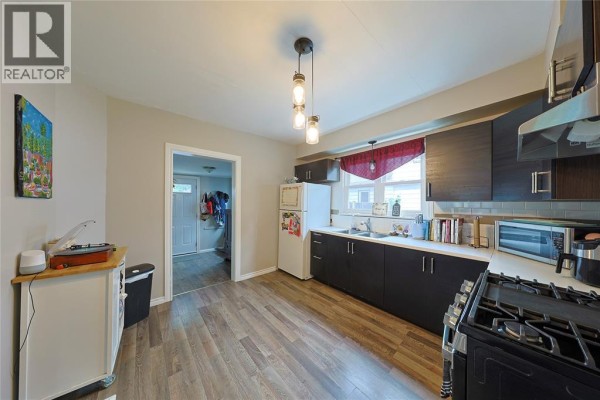 Kitchen with dark cabinets, white countertops, stainless steel appliances, and wood-look flooring. - 414 Davis Street, Sarnia